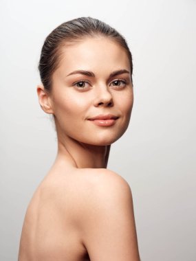 Kusursuz ciltli genç bir kadının portresi güzellik konsepti fotoğrafçılık oturumunda beyaz bir arka plana poz veriyor.