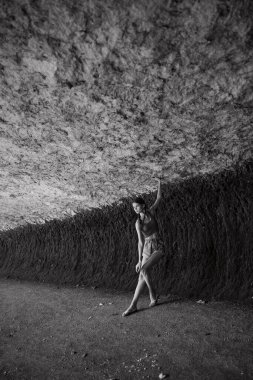 Görkemli kaya oluşumunun önünde duran bir kadın siyah-beyaz seyahat macerası fotoğrafında.