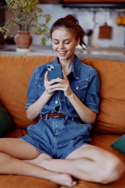 Bacak bacak üstüne atmış, elinde cep telefonu olan rahat bir kadın.