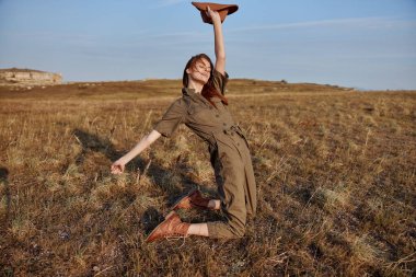 Tarlada şapkalı bir kadın, doğanın ve özgürlüğün tadını çıkarıyor, yaz macerası konsepti.