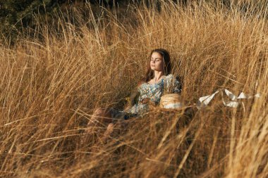 Uzun çimenlerde oturan bir kadın şapka serüvenleri serüvenleri, açık hava güzelliği, rahatlama yaz tatili, doğa gezisi edebiyat eğitimi, kadın portresi kavramsallaştırılmış.