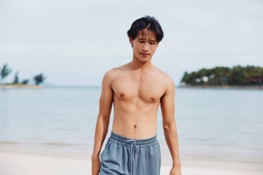 Aktif Asya Sporcusu: Enerjik bir Sahil Çalışması - Kumda Koşan Kaslı Adam, Sağlıklı Yaşam Tarzını Kucaklıyor