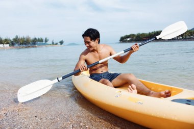 Maceracı Asyalı Adam Tropikal bir plajda kayak yapıyor.