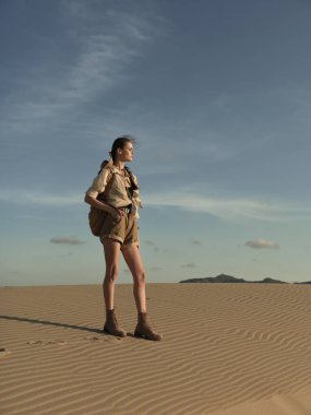 Lonely woman standing in the vast desert landscape, gazing into the unknown horizon clipart