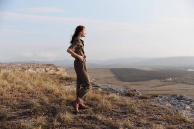 Kadın, seyahat ve macera konsepti için tepenin tepesindeki vadi ve dağların muhteşem manzarasının keyfini çıkarıyor.