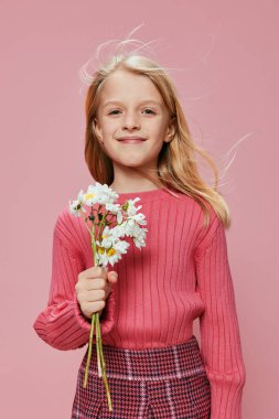 Pembe elbiseli neşeli küçük kız, elinde bir buket çiçek, Anneler Günü 'nü kutluyor. Parlak gülüşü ve ışıltılı gözleri çocukluğun mutluluk ve büyüsünü yansıtıyor.