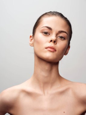 Doğal ve ışıl ışıl genç bir kadının portresi, berrak bir güzellikle beyaz bir arka planda zarif bir şekilde duruyor.