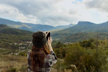 Huzurlu bir yolculuk sırasında dağların görkemli güzelliğini cep telefonuyla yakalayan bir kadın.