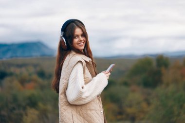 Dağ Özgürlüğü: Yürüyüş Macerasında Gülümseyen Kadın, Siber alemde akıllı telefonuyla selfie çekiyor.