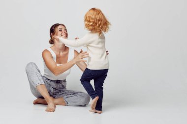 Aile bağlarını pekiştiren anne ve kız oturma odasında ellerle neşeyle oynuyorlar.