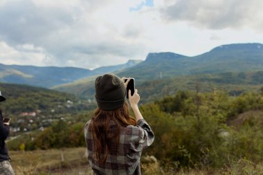 Çift nefes kesici dağ manzarasından zevk alıyor, akıllı telefonlarıyla seyahatlerindeki güzelliği yakalıyorlar.