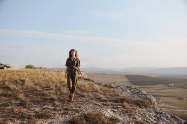 Kadın tepenin üstünde çantasıyla duruyor seyahat ve macera konsepti için doğanın çarpıcı manzarasının tadını çıkarıyor.