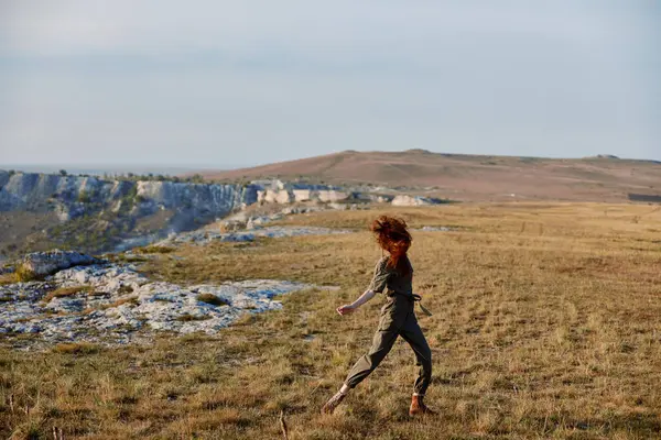 stock image Woman running in grassy field with mountain in background, nature adventure beauty trip concept