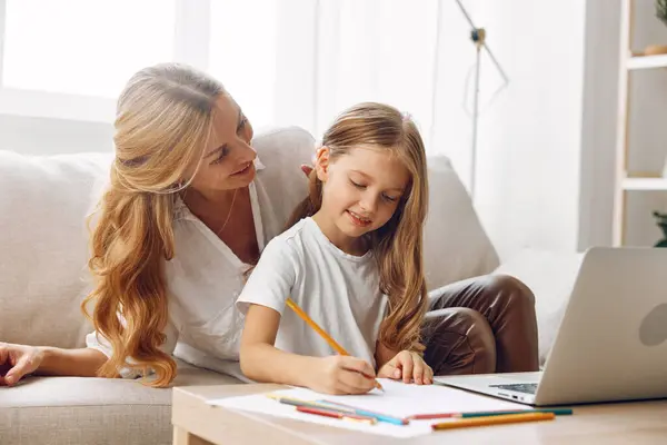 stock image Mother and daughter collaborating on homework with laptop on cozy home couch