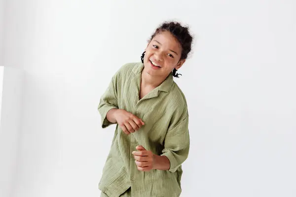 stock image Stylish young boy in green outfit strikes pose against white wall in trendy urban setting.