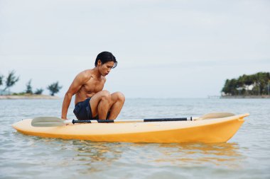 Idyllic Kayak Macerası: Tropikal Sahilde Doğada Egzersiz Yapan Mutlu Asyalı Bir Adam.