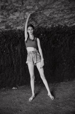 Şort ve kolsuz gömlekle muhteşem kaya oluşumunu keşfeden bir kadın gezgin siyah ve beyaz fotoğrafla maceraya çıktı.