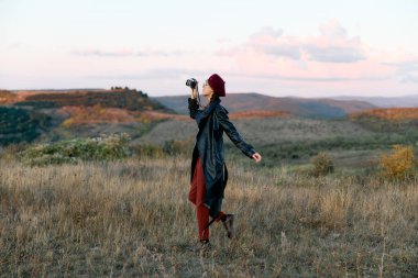 Elinde kamerayla renkli kır çiçekleriyle doğanın canlı güzelliğini yakalayan bir kadın..