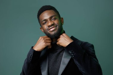 Zarif siyah smokinli, sakin ve çekici tavırlarıyla dimdik duran kendinden emin genç bir adam..