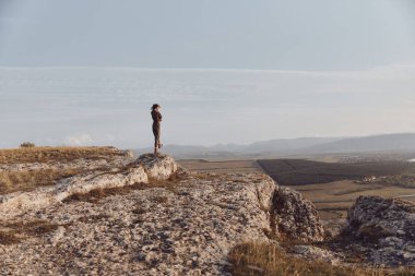 Dağın tepesinden, vadiden ve tepelerden nefes kesici manzaranın tadını çıkarıyorum.