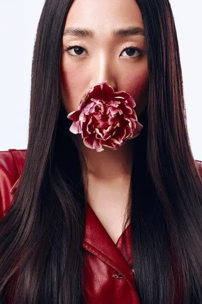 stock image Mysterious woman with long black hair and a flower covering her mouth in a captivating pose