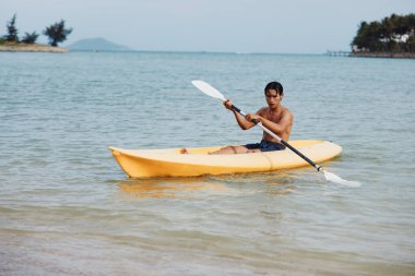 Tropikal Cennet 'te kayak yapan Asyalı Maceracı Adam: Sahilde Eğlenceli Bir Yaz Tatilinin Tadını Çıkarıyorum