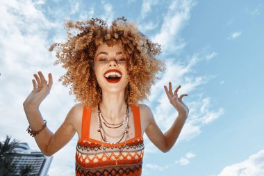 Mutlu Sahil Gezgini Gülümseyen, Açık Ağızla Dans Eden: Geniş Açı Mercek İçinde Kıvırcık Saçlı Bir Kadının Neşeli Portresi Doğa Güzelliği ve Okyanuslar Mavisi