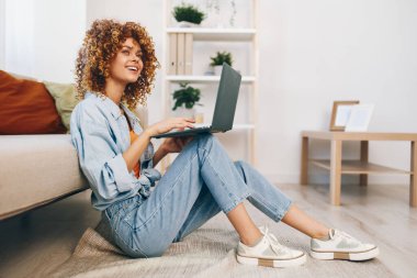 Samimi bir ofiste dizüstü bilgisayarda çalışan gülümseyen kadın.