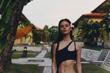 Plaj kıyısında, Palm Tree 'nin önünde duran Siyah Parça Mayo Giyen Tropikal Tatil Kadını