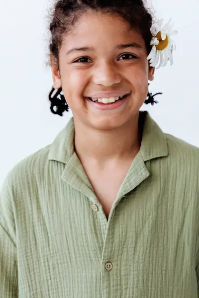 stock image A portrait of a young african american boy embracing nature with a flower in his hair, exuding a trendy and carefree vibe.