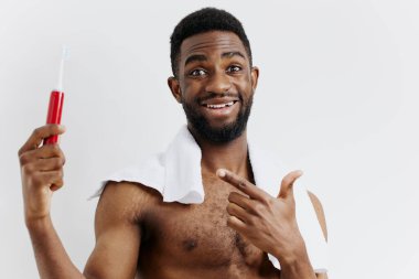 Diş fırçası ve diş macunu tutan gömleksiz bir adam, banyoda duruyor, sabah hijyen rutinine başlıyor..