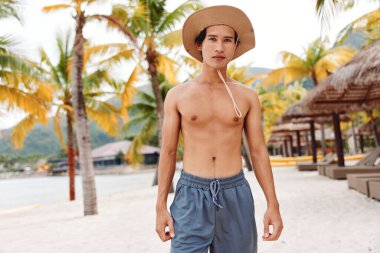 Gülümseyen Asyalı Adam Tropikal Sahilde Tatilin keyfini çıkarıyor