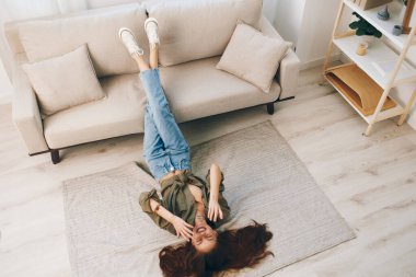 Modern bir apartmandaki rahat bir koltukta rahatlamak: Mutlu bir kadın Zihinsel Sağlığın ve Sağlıklı Yaşamın tadını çıkarıyor