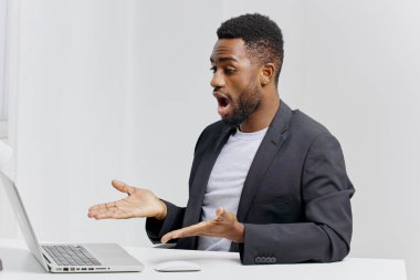 Şok olmuş bir ifadeyle iş adamı. Laptop ekranına bakıyor. Modern bir ofiste masa başında oturuyor..