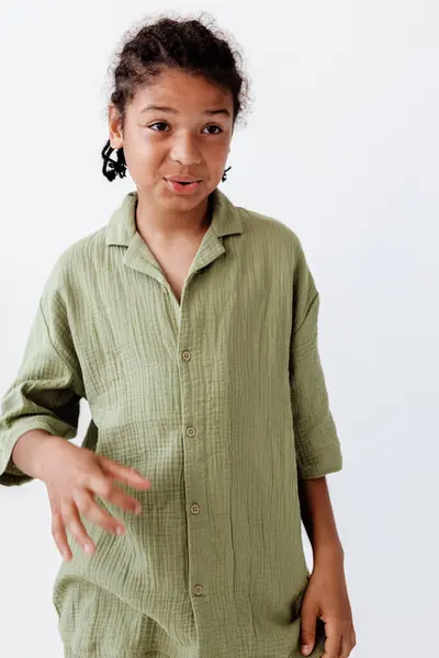 stock image Stylish young boy in green shirt strikes a trendy pose with hand to side of face, exuding fashionable confidence.