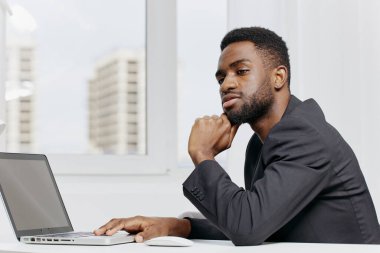 Takım elbiseli kendine güvenen bir işadamı, özenle laptopuyla modern bir ofis masasında çalışır..