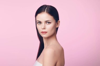 Akan siyah saçlı çekici genç bir kadın stok fotoğrafında pembe bir arkaplana karşı poz veriyor. Moda çekimlerinde güzellik ve güven yayar..