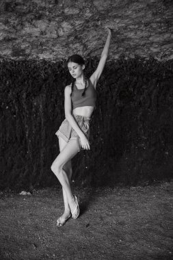 Moda fotoşopu sırasında seyahat dergisi için taş duvarın önünde poz veren genç bir kadın.