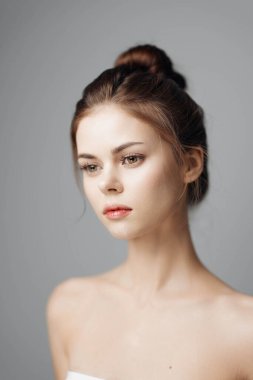 Stüdyo çekimlerinde gri arka planda beyaz havlusu olan güzel bir genç kadının portresi..