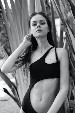 Plajda dinlenen Siyah Giysili Kadın ile Tropik Palmiye Ağaçları Arkaplanı