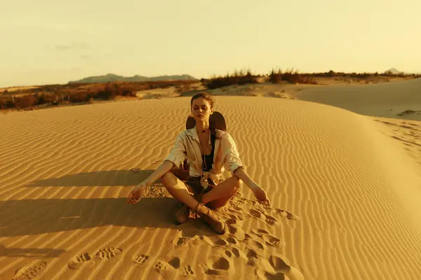 stock image Woman meditating peacefully in the vast desert landscape with her eyes closed and sand all around her