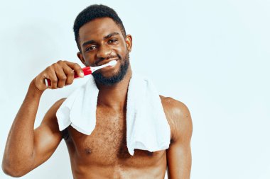 Gömleksiz adam ağız temizliğine odaklanmış, diş fırçasıyla diş fırçası fırçalama, sabahın erken saatlerinde banyoda..