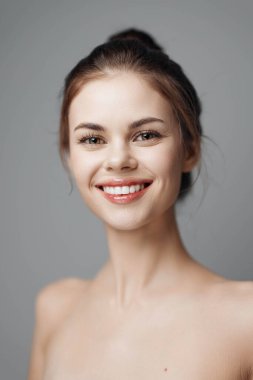 Gri arka planda güzel bir gülüşü olan genç bir kadın, beyazda soyutlanmış. Stok resimleri araması için uygun bir portre fotoğrafı.