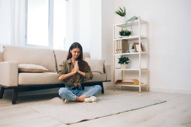 Konforlu Yaşam: Mutlu bir kadın rahat dairesinde modern bir koltukta meditasyon yapıyor