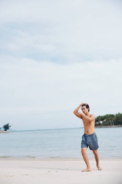 Aktif Asyalı atlet Sunset 'te plajda koşuyor, kaslı bir vücutta güç ve güç yayıyor.