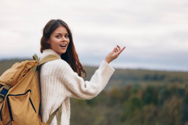 Gülümseyen kadın nefes kesici doğayla çevrili maceralı bir dağ yürüyüşünden zevk alıyor.