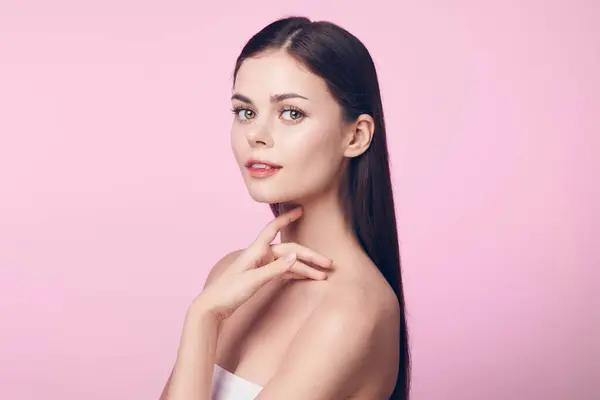 stock image Beautiful young woman with long straight hair posing on pink background with hand on chin looking at camera. image is royalty-free and perfect for various projects.