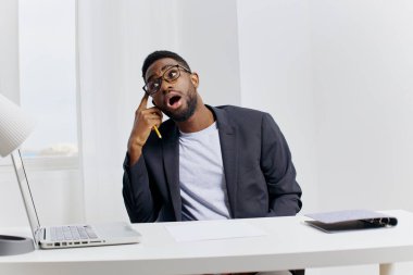 Takım elbiseli bir iş adamı, masadan laptopuyla modern ofis ortamında bir telefon görüşmesi yapıyor..