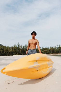 Mutlu Asyalı Adam Tropikal Sahilde Kano Macerasının tadını çıkarıyor