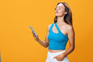 Şık giyinmiş çekici genç bir kadın telefonunu tuhaf bir ifadeyle kontrol ediyor.